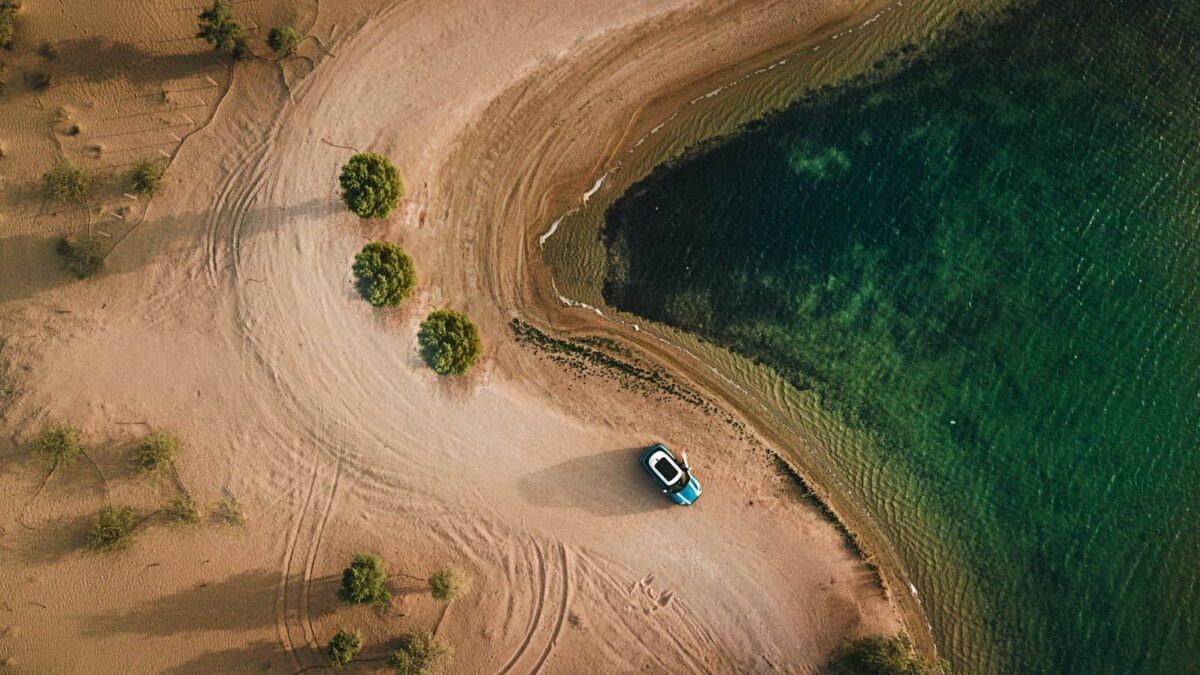 aerial-photography-of-vehicle-parked-on-beach-near-bushes-1443657