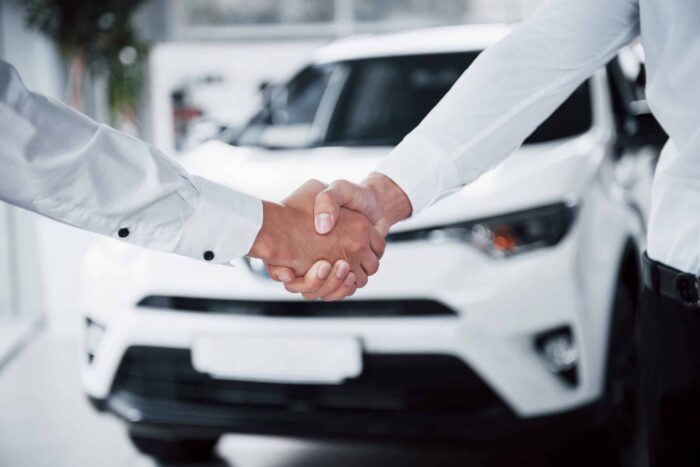 close up sales manager black suit selling car customer scaled 1