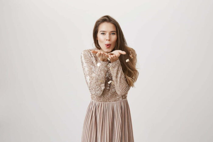 feminine woman blowing golden confetti evening dress