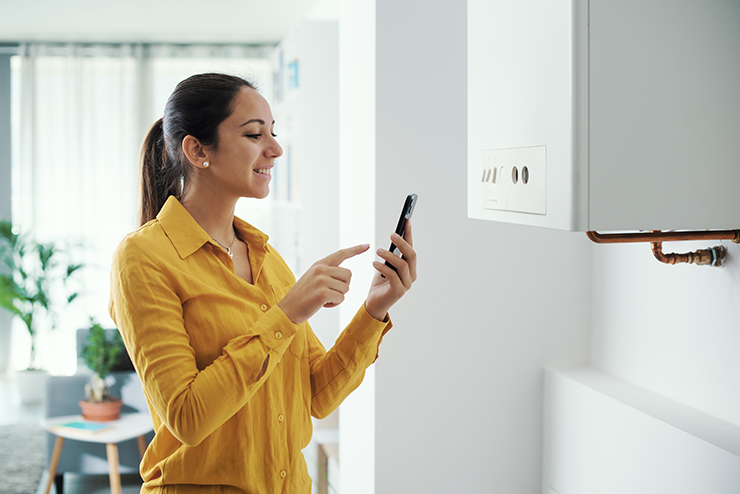 Proiecte de bricolaj rentabile pentru iarnă Imaginea unei femei la telefon care își programează centrala inteligentă