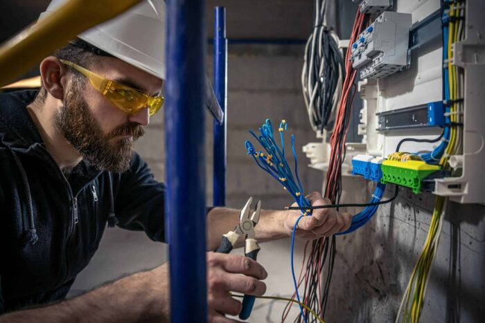 male electrician works switchboard with electrical connecting cable 3 scaled