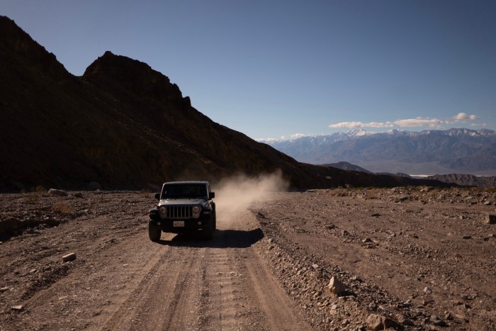 Un jeep care conduce pe un drum prăfuit