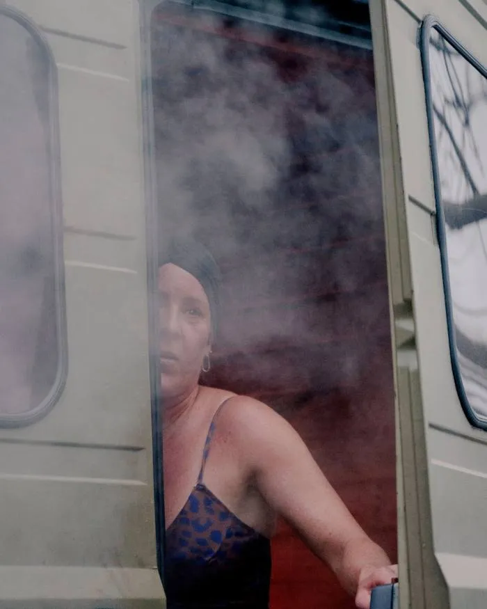 O femeie în costum de baie, privind pe ușa din spate de la duba saună Butcher's Heat