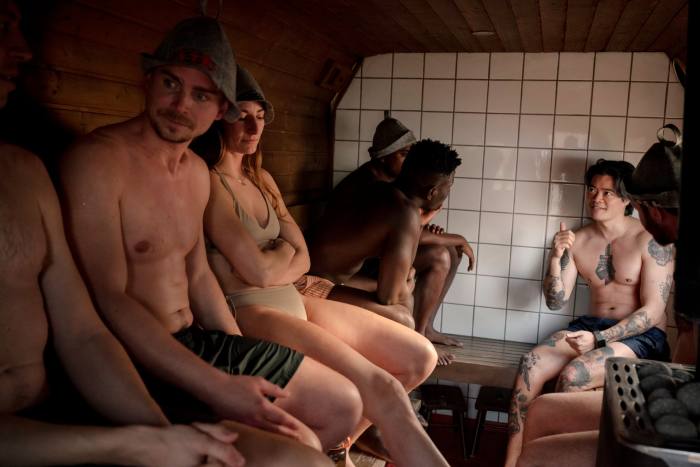 Bărbați și femei în trusă de baie și pălării ascuțite din pâslă care stăteau în sauna Butcher's Heat