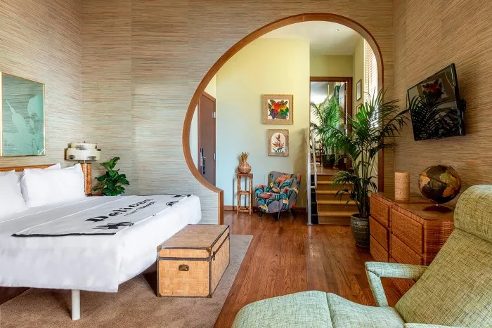 O suită de hotel cu intrare rotunjită în peretele dintre dormitor și zona de relaxare