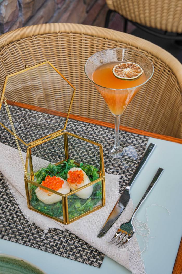 O salată de ouă într-o cutie de sticlă pe o masă, lângă un cocktail de culoare portocalie