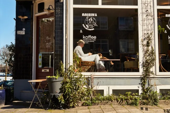 Marcelis stă la o masă din fereastra Raisin the Bar, un bar de vinuri naturale din Rotterdam