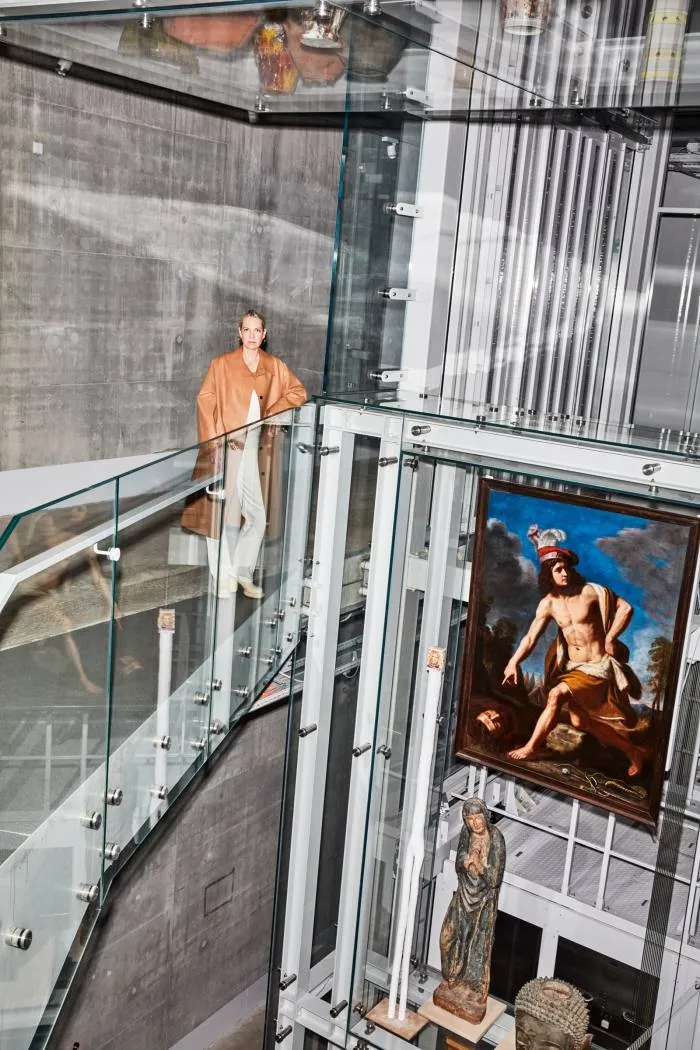 Marcelis pe o pasarelă înălțată în interiorul Depot Boijmans Van Beuningen, cu o pictură religioasă și o icoană sub ea, la dreapta