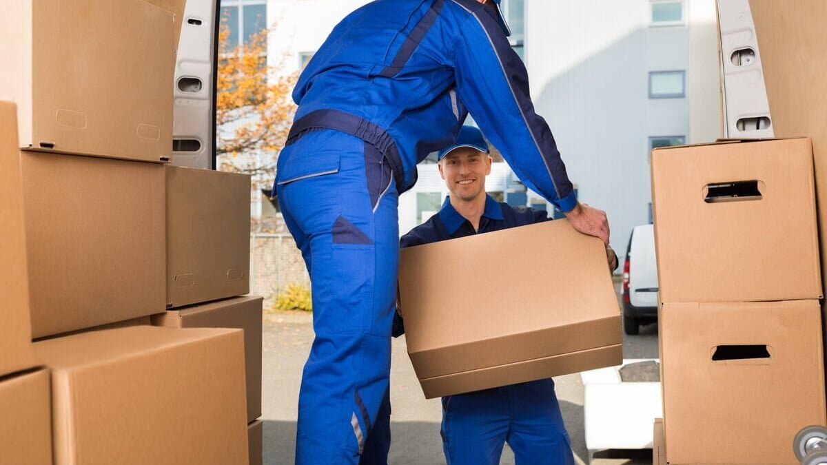 Movers Carrying Sofa Outside Truck On Street