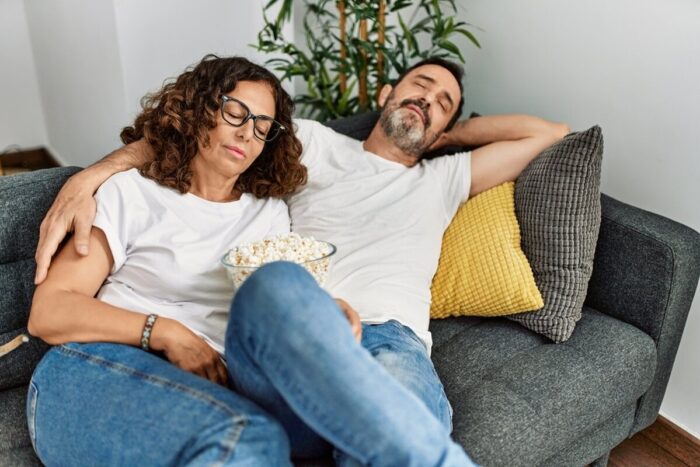 Middle,Age,Hispanic,Couple,Sleeping,Sitting,On,The,Sofa,At