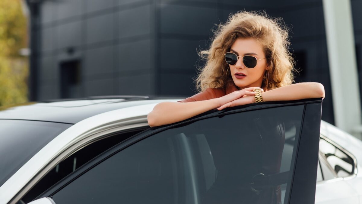 Care este arta de la mulţumirea de sine la fericire? confident woman formal dress outdoors posing near her white car
