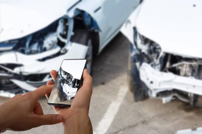 man photographing his vehicle with damages accident insurance with smart phone 1024x683