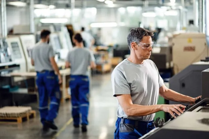 mid-adult-worker-operating-cnc-machine-while-working-industrial-facility-scaled.jpg