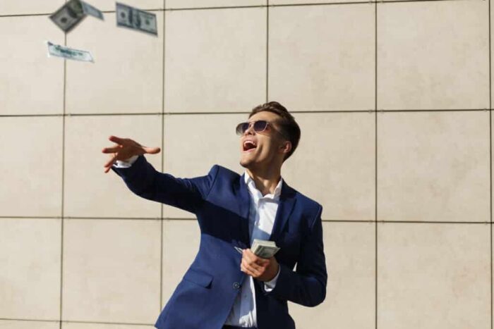 young businessman throughs around dollars dances street 1024x683