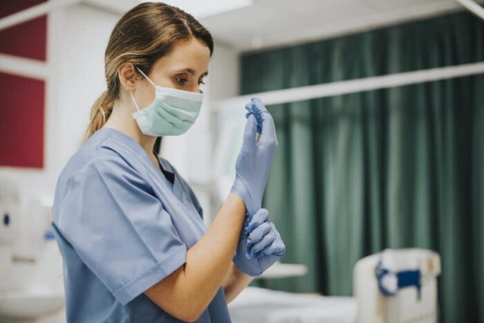 female nurse with mask putting gloves 1024x683
