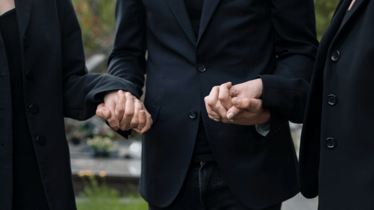 familie indoliata care se tine de mana petru funerare