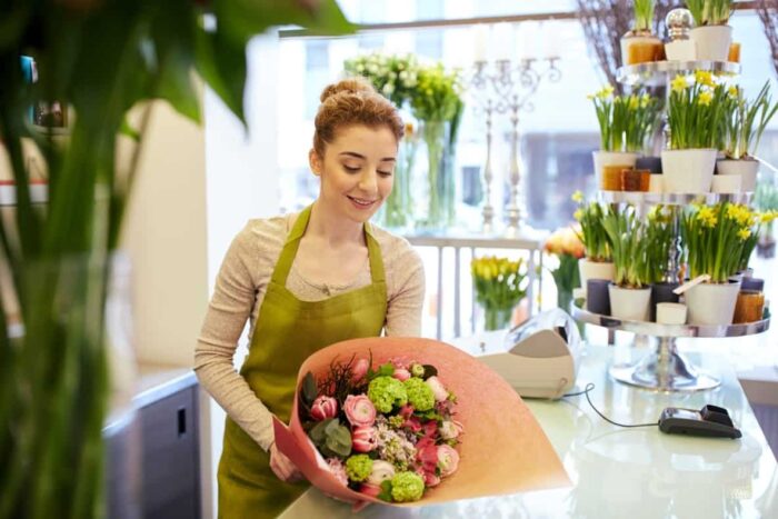people business sale floristry concept happy smiling florist woman wrapping bunch into paper flower shop