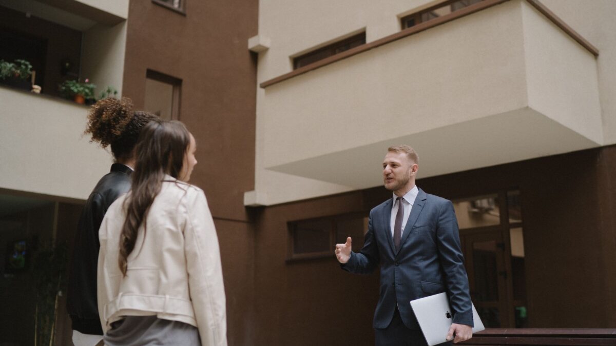 Agent imobiliar discuta cu doi clienti in curtea