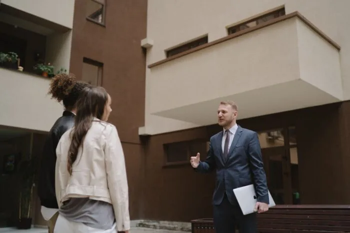 Agent imobiliar discuta cu doi clienti in curtea