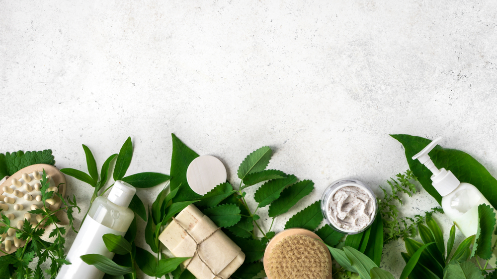 Natural,Cosmetics,And,Green,Leaves,On,White,Stone,Background,,Copy