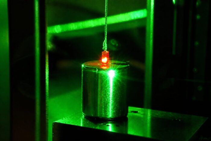 Un mic obiect suspendat iluminat de un laser în laborator