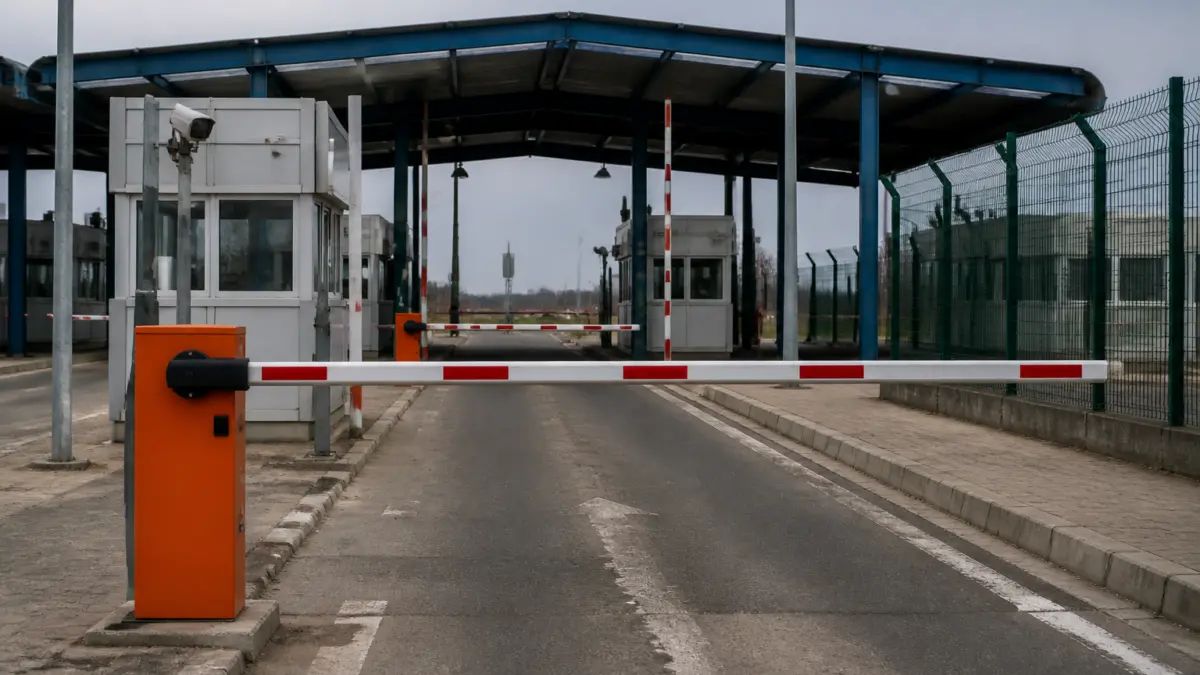 Un punct de control la frontieră cu o barieră portocalie coborâtă în prim-plan